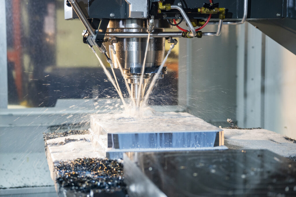 A modern CNC milling machine cutting steel in an industrial manufacturing machine shop.