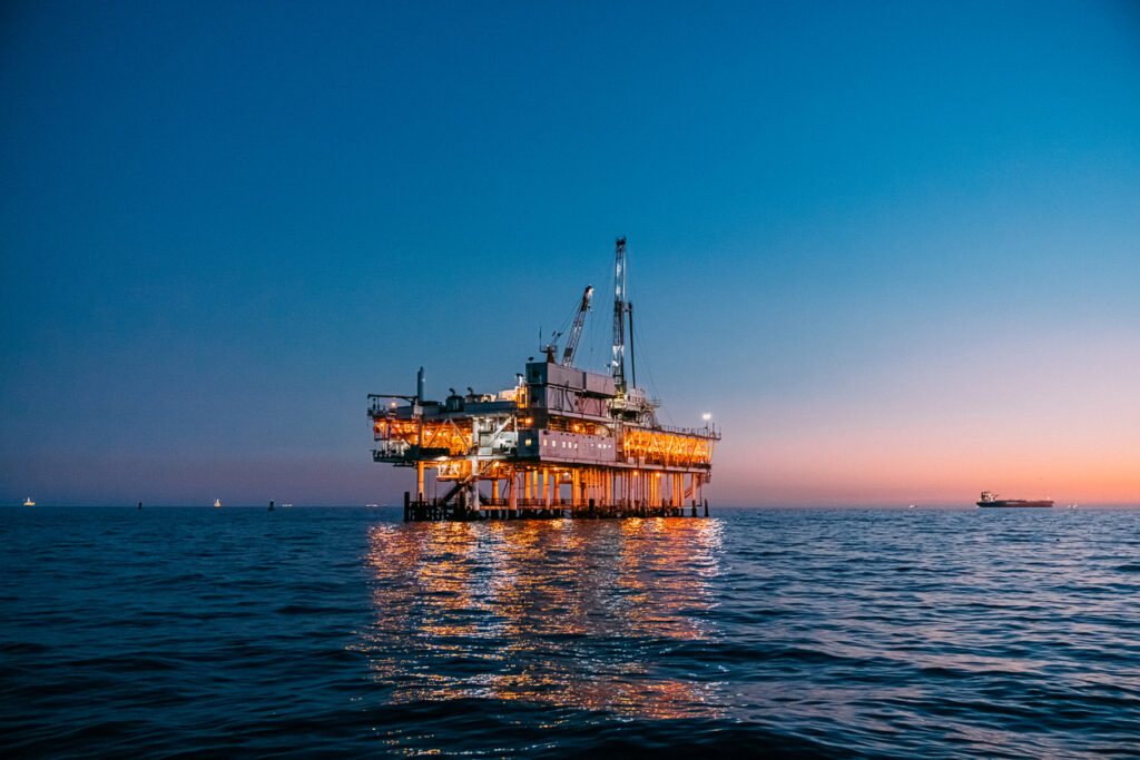 Offshore oil and gas platform operating at sunset in the ocean.